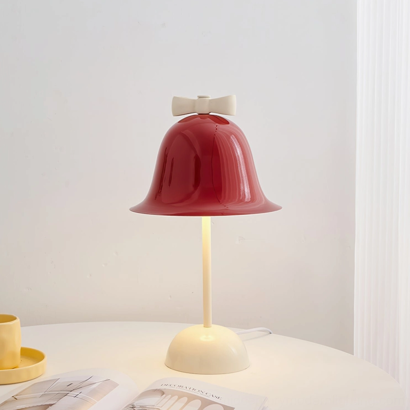 Bow Bell table lamp styled on white round side table with yellow cup and saucer, home design magazines, interior décor setup