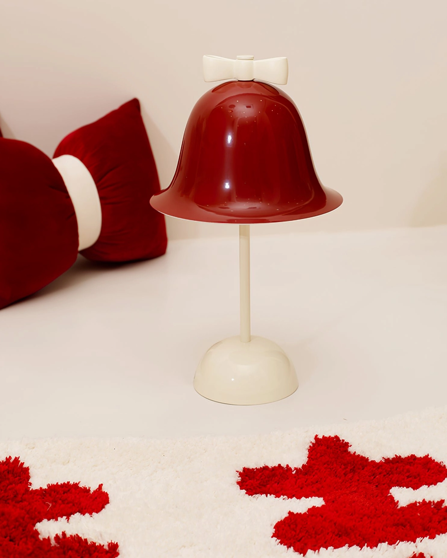 Bow Bell table lamp three-quarter view showcasing elegant design, burgundy red bell shade, and cream white metal construction