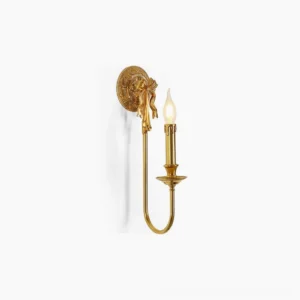 Bow brass wall sconce with curved arm and polished gold finish in studio setting