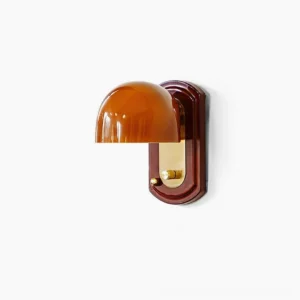 Bradley mid-century modern wall sconce with retro red amber glass dome, dark wood backplate and brass hardware mounted on white wall