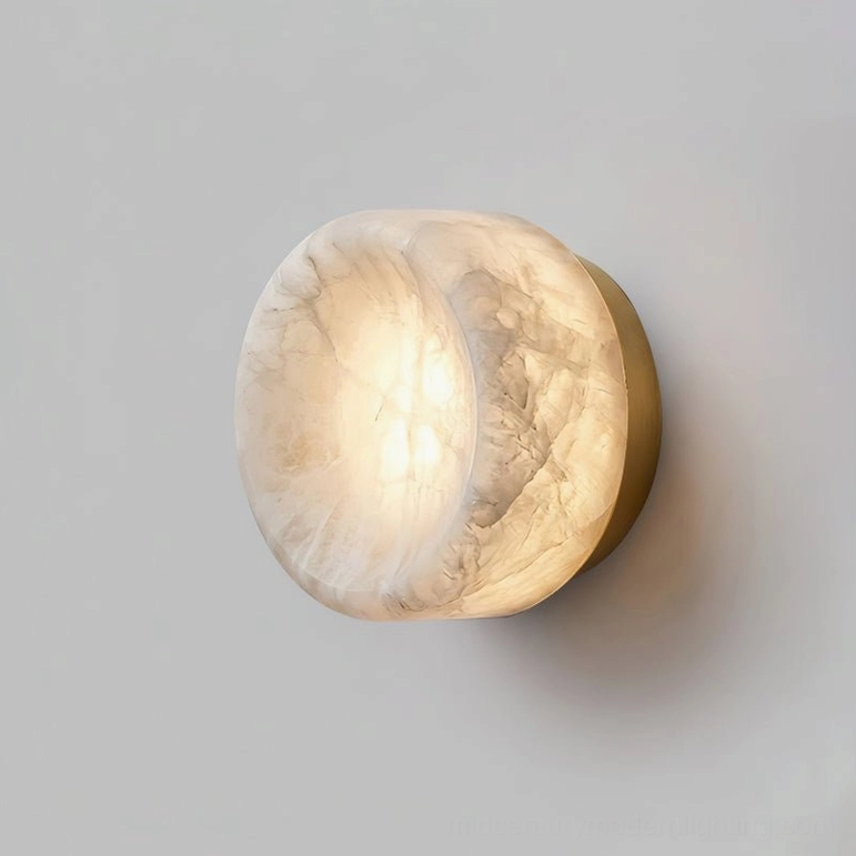 Alabaster disc wall sconce with brushed brass base and warm LED showing stone translucency and light diffusion