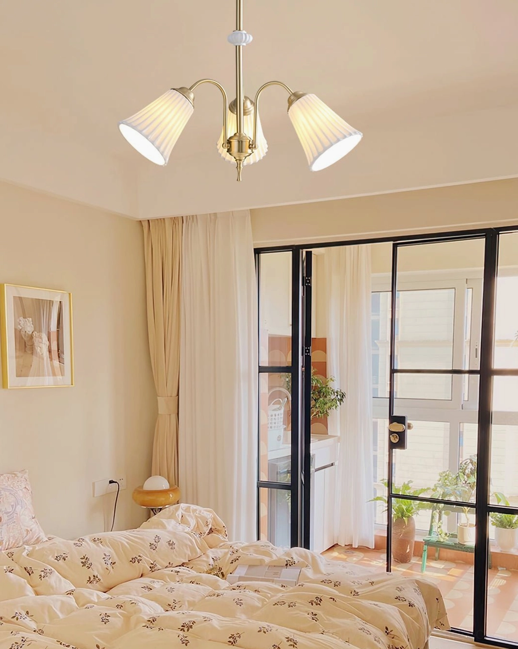 3-head brass chandelier with pleated glass shades in cozy bedroom interior with glass balcony door, warm minimalist home style