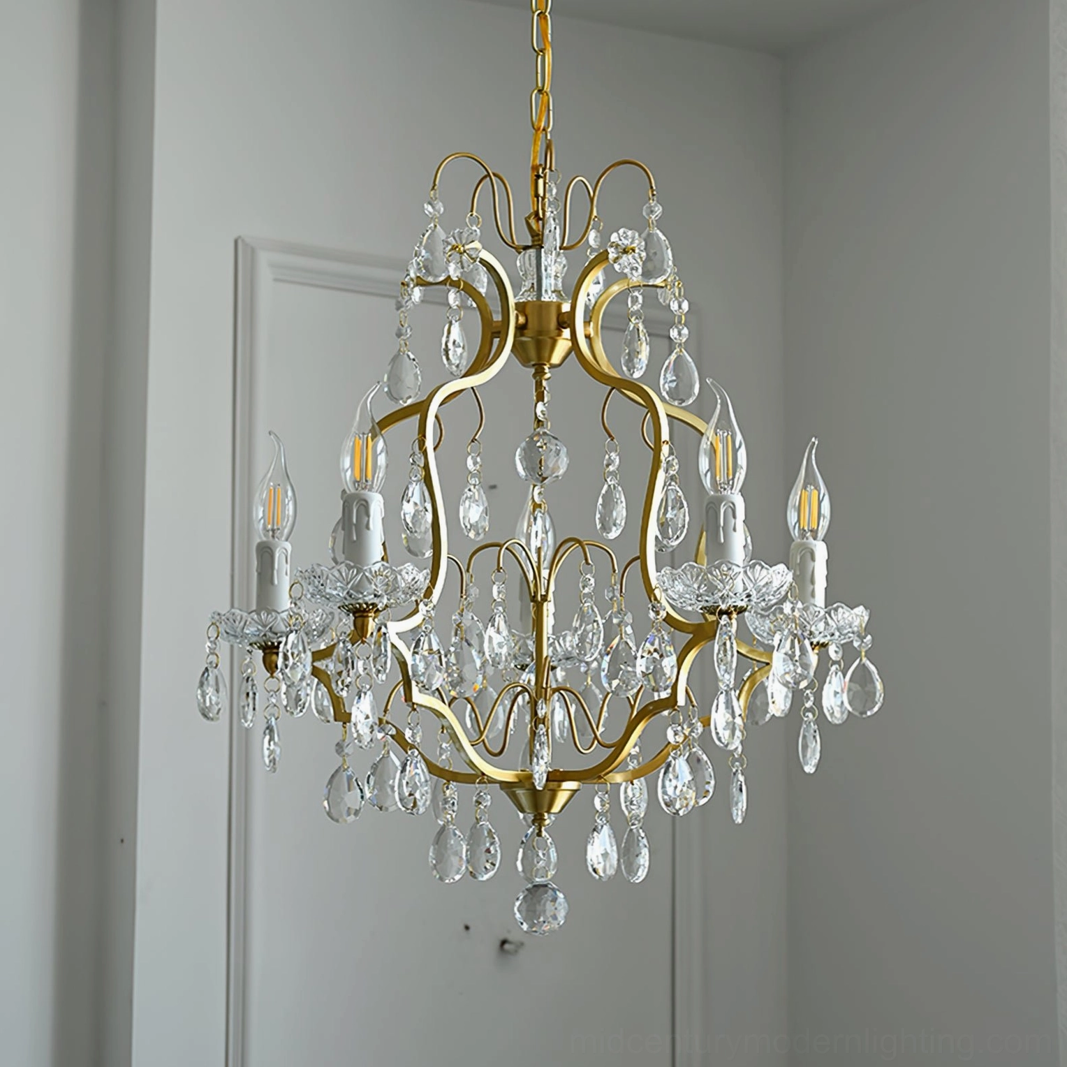 Sleek curved gold arms brass chandelier with small crystal pendants and candle-style bulbs