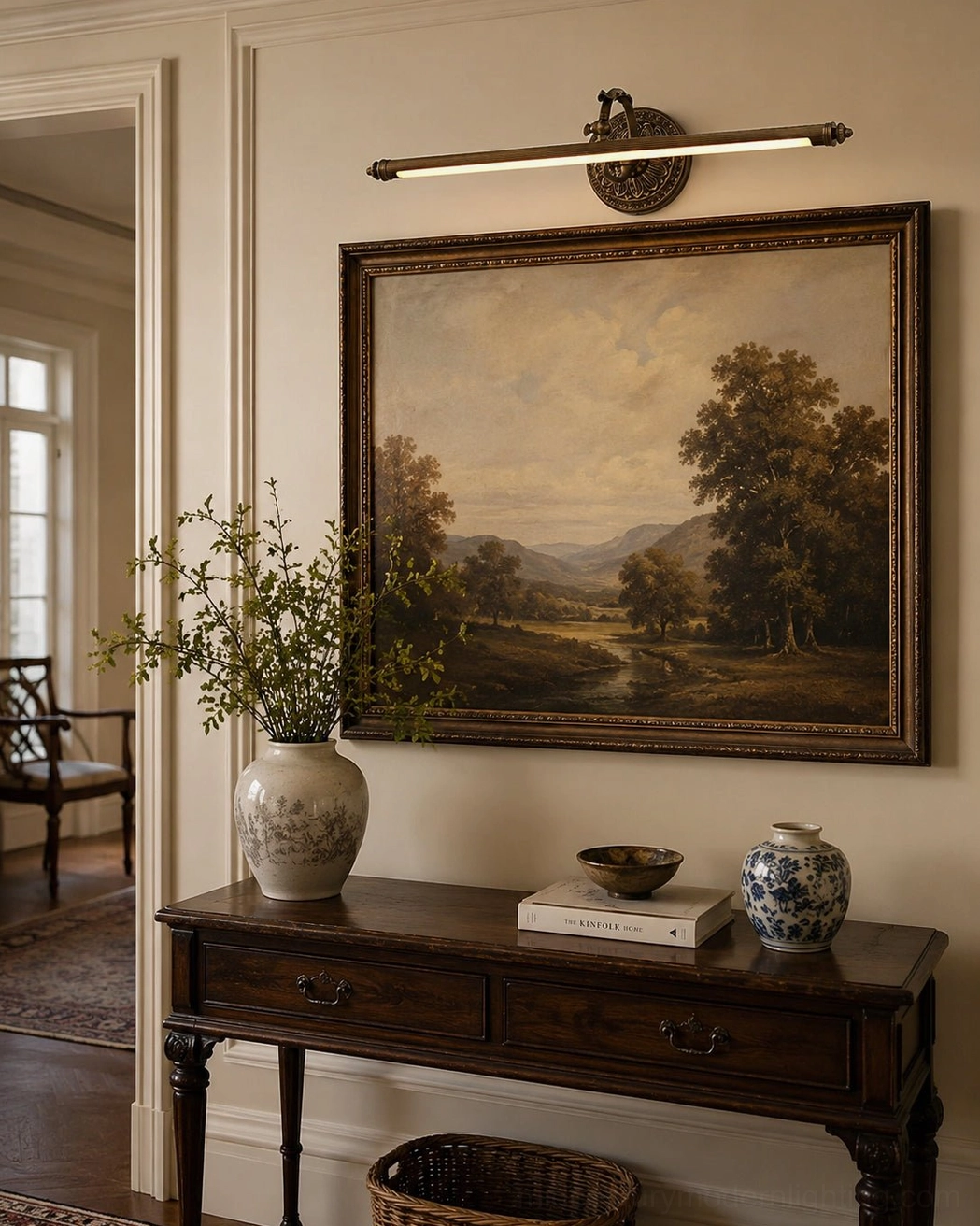 Warm brass wall sconce with reeded bar and finials mounted above wooden console table in formal living room