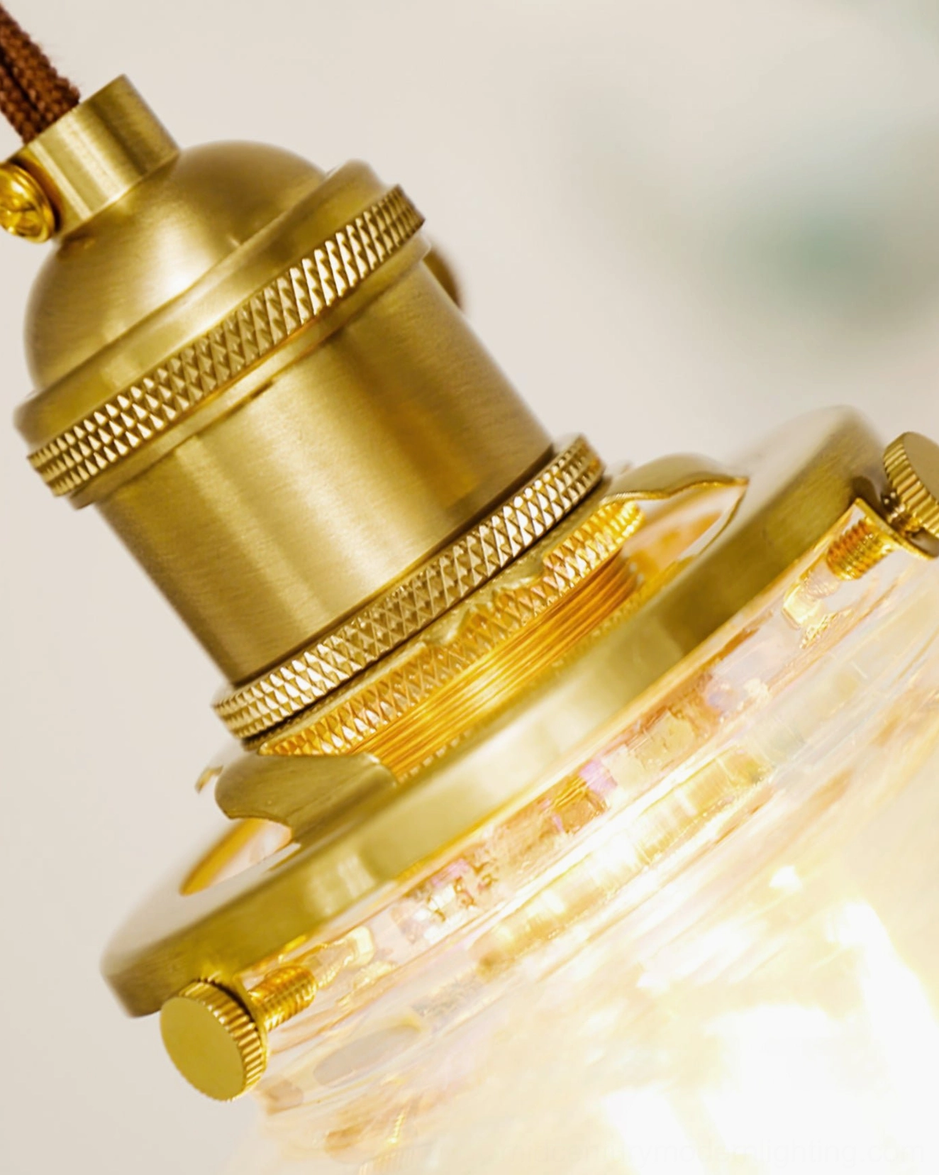 Close-up detail of polished brass crown and E14 bulb socket on water droplets resin pendant