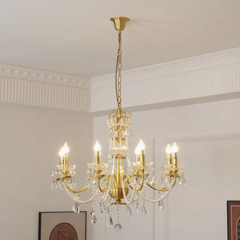 Gold finish brass crystal chandelier with 8 light arms and hanging crystal droplets in French-style room