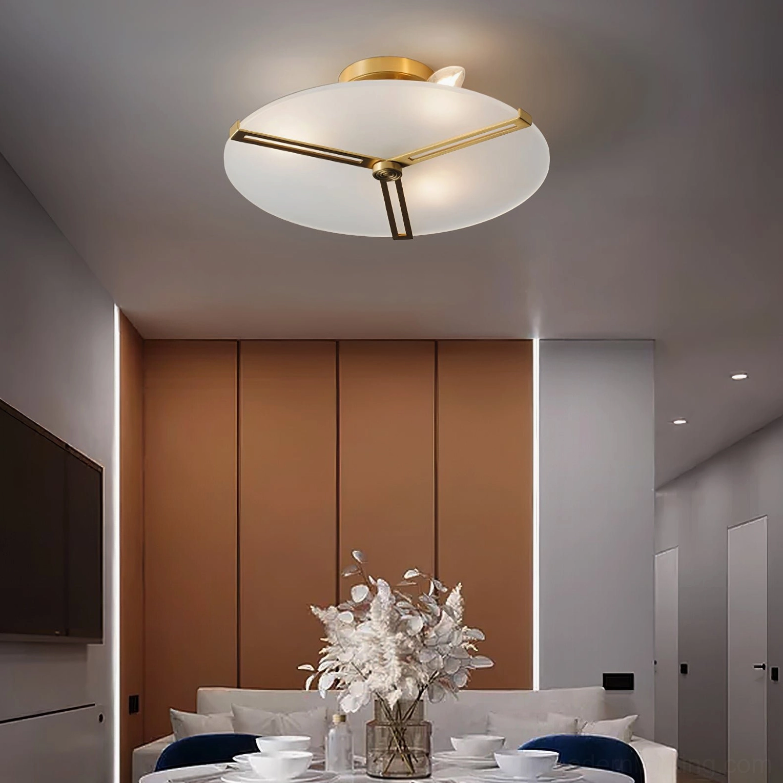 Brass ceiling lamp providing warm ambient light in minimalist dining area with floral centerpiece