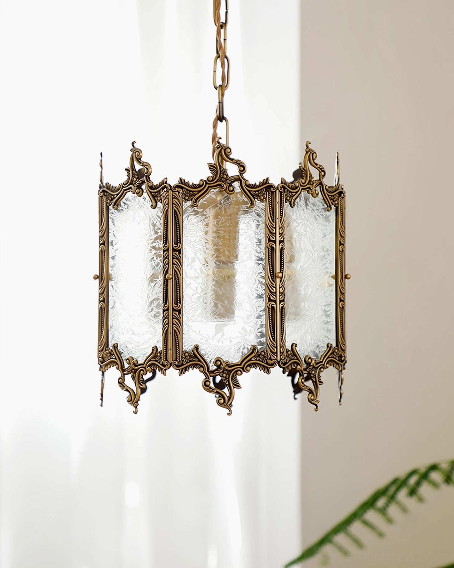 Antique brass glass pendant lantern three-quarter view showing rectangular glass panels and brass chain hanger in bright indoor space