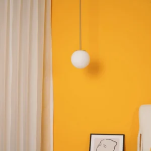 Modern brass pendant light in bedroom with warm orange accent wall creating ambient illumination