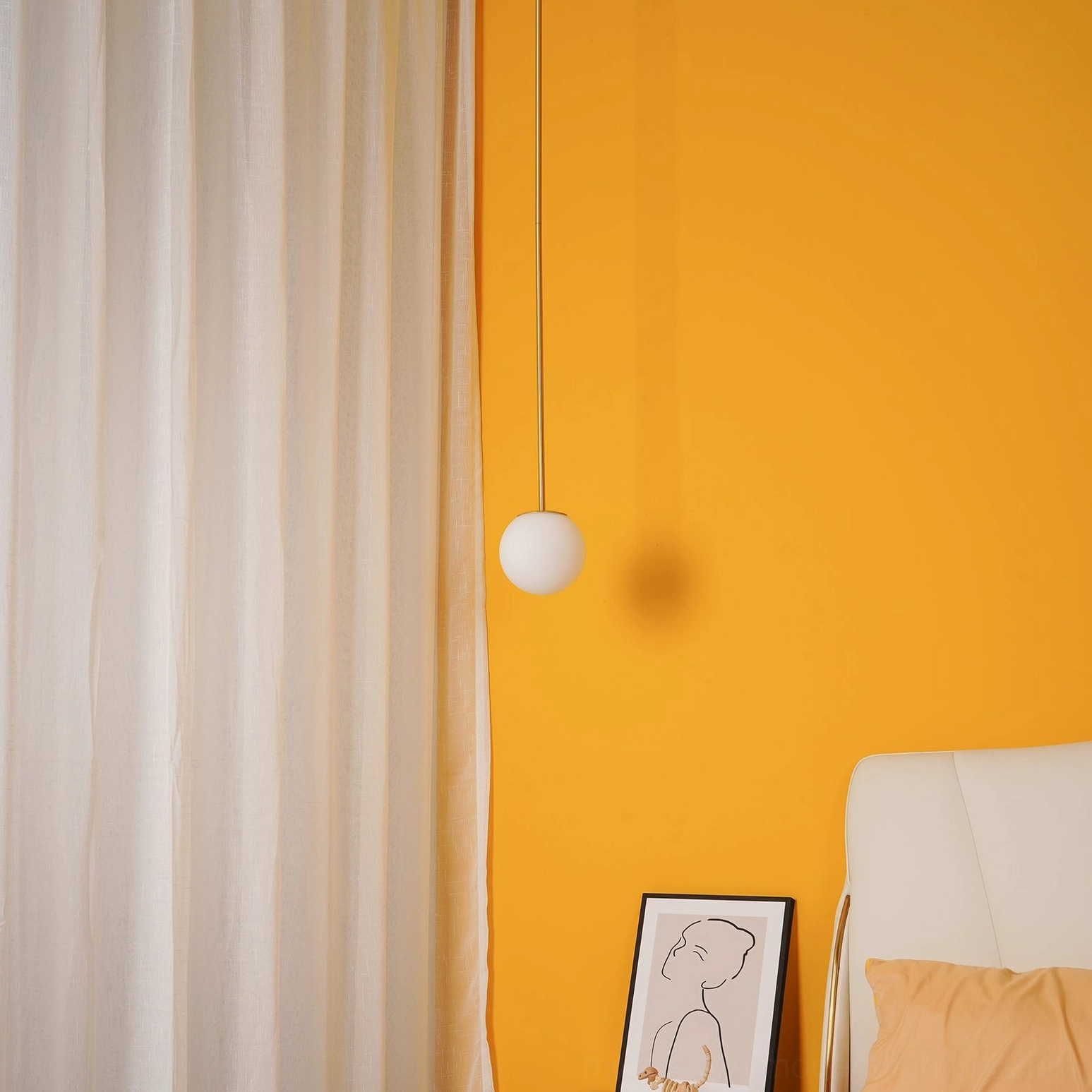 Minimalist brass suspension pendant fixture in cozy bedroom corner setting
