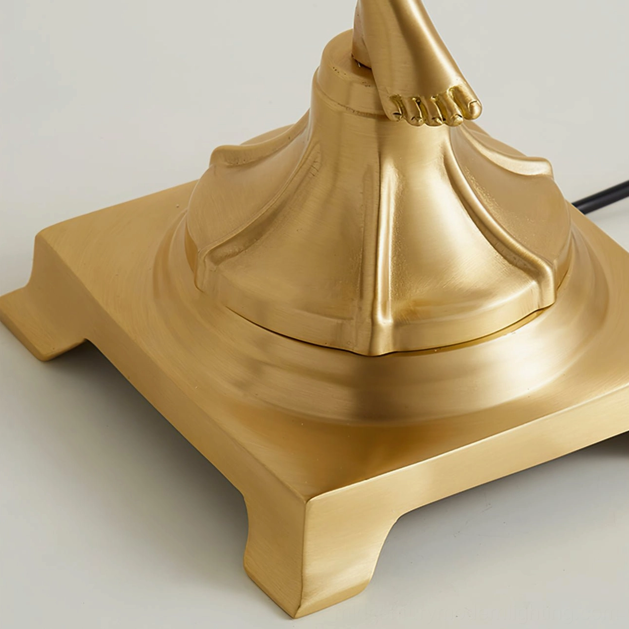 Top-down view of square footed brass base with smooth polished metal texture supporting cherub angel sculpture