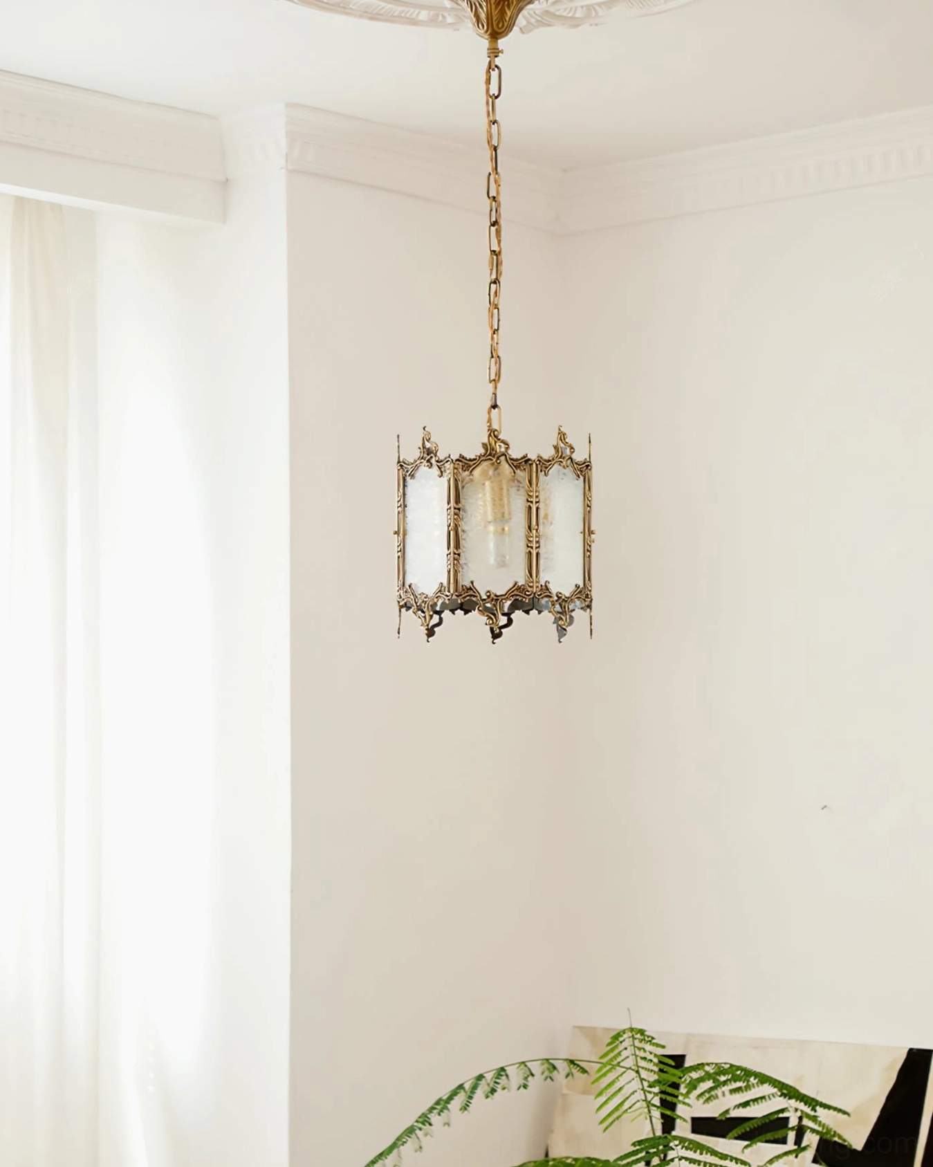 Ceiling-mounted brass lantern pendant light overhead view showing hardware and hanging mechanism in bright minimalist interior