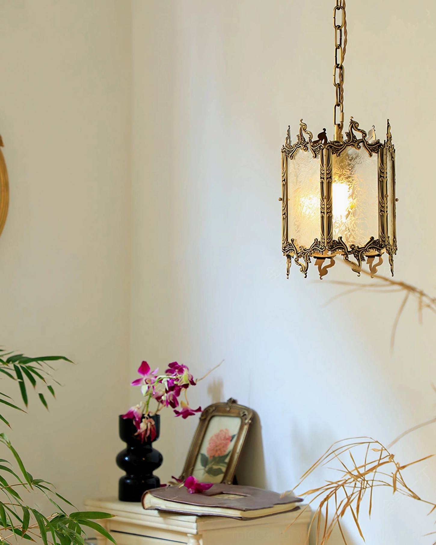 Brass lantern pendant hanging in minimalist home corner with side table and potted orchid accent, neutral interior setting