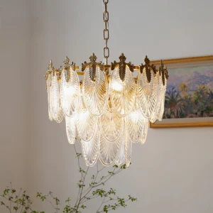 Illuminated three-tier brass chandelier with warm glow in transitional living room with framed wall art and green plants