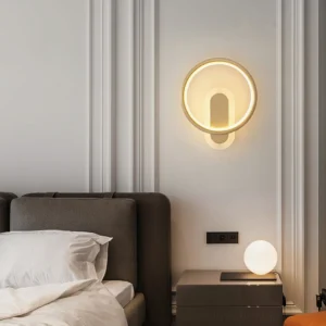 Modern brass wall sconce mounted in luxury bedroom with tufted headboard warm lighting