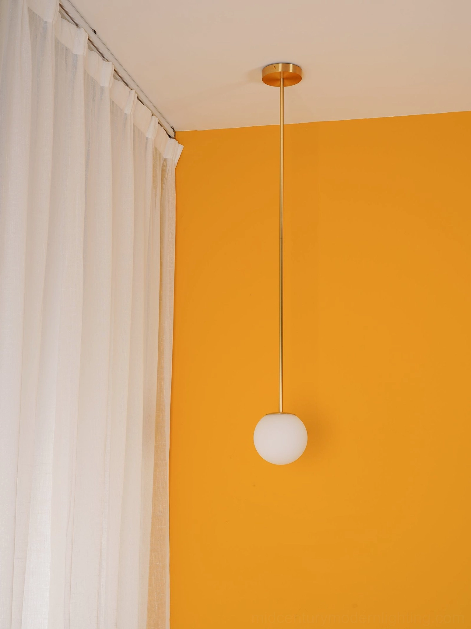 Gold brass ceiling pendant with frosted opal globe in minimalist bedroom design