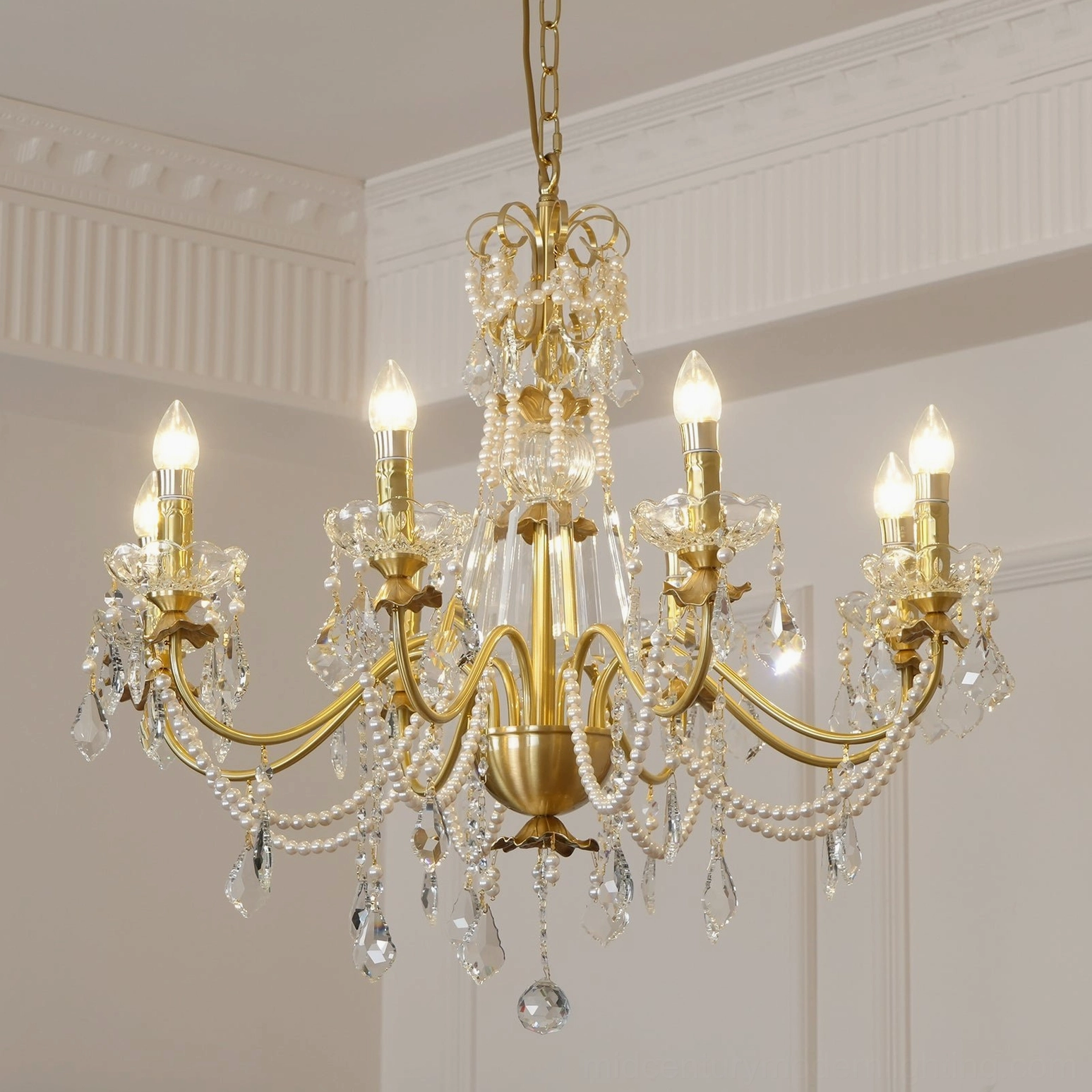 Brass and crystal chandelier with decorative pearl elements in ornate French-style room setting