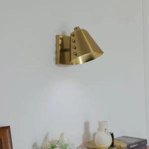 Mid-century modern brass wall sconce side view in dining room with warm ambient lighting and adjustable angle