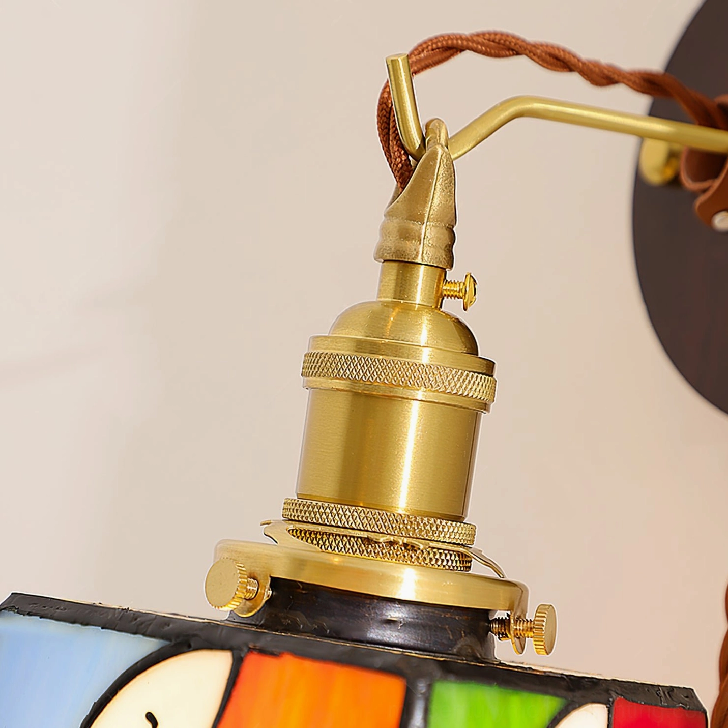 Overhead close-up of brass adjustable socket and locking adjustment knobs on lamp arm assembly
