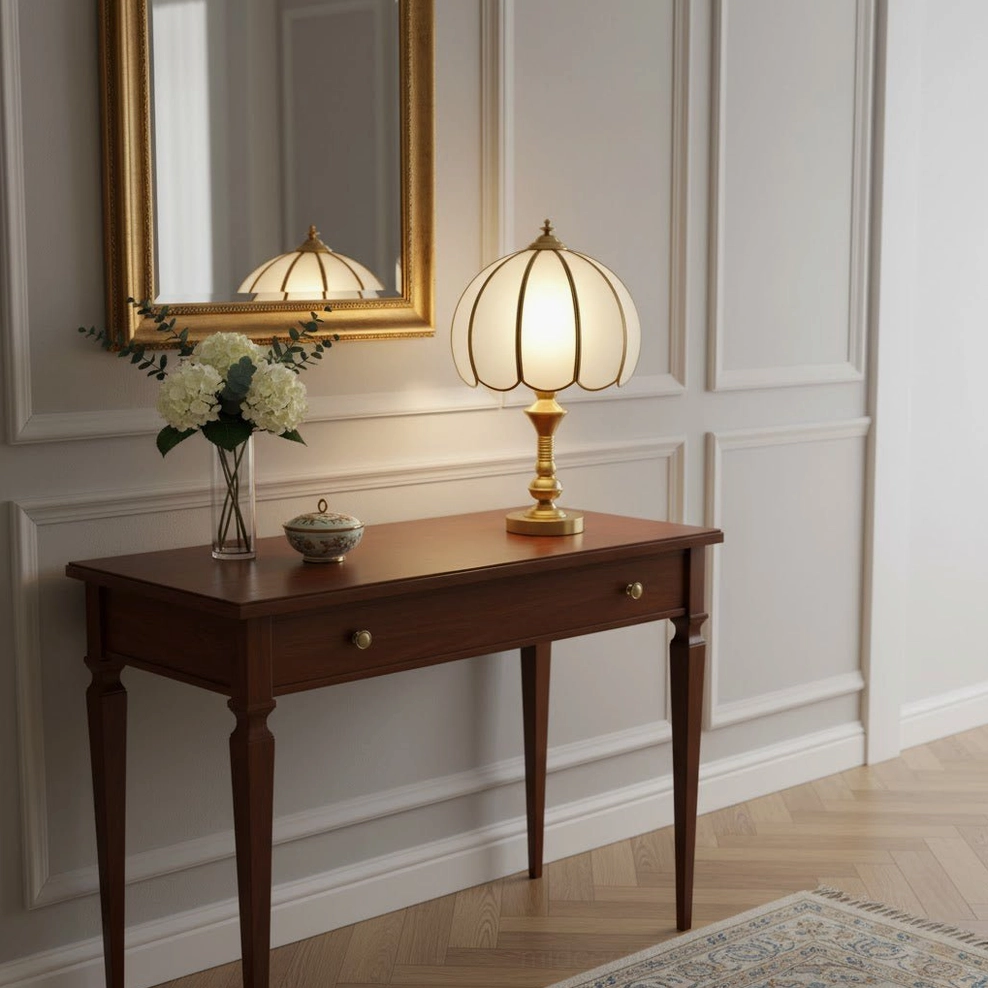 Brass table lamp on side table with gold framed mirror and floral decor, indoor wall paneling background