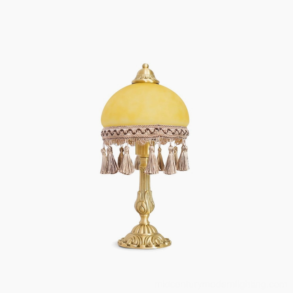 Vintage brass table lamp with yellow frosted glass dome and tassel trim, front view on white background