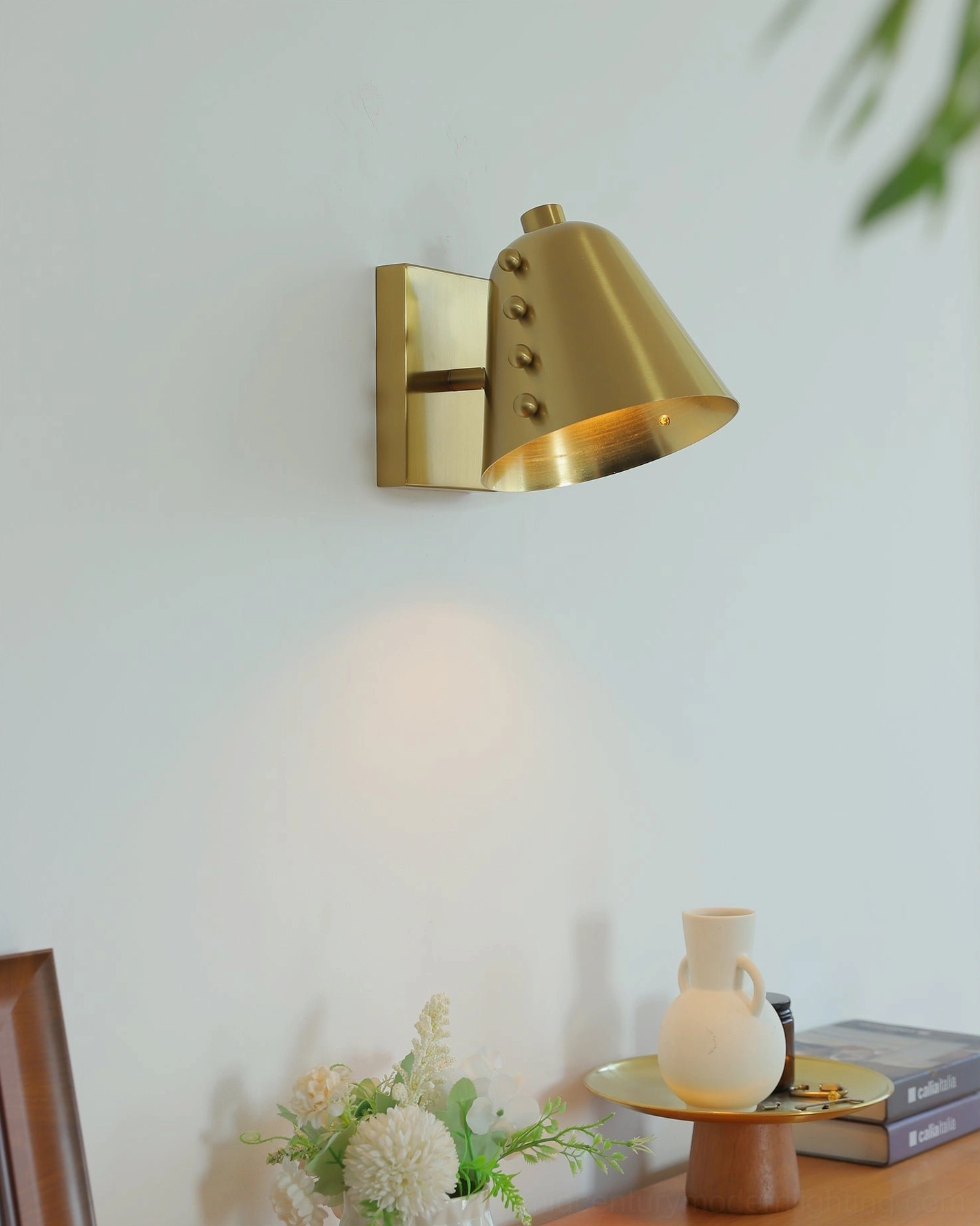 Brass wall lamp upper perspective tabletop display with tapered shade glowing warm light mid-century modern