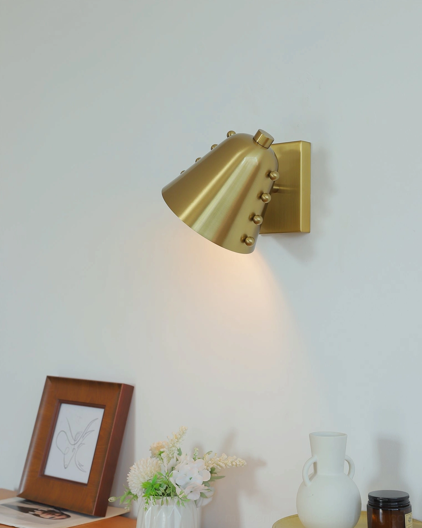 Brass wall light left side eye-level view with angled shade and studded finish details contemporary