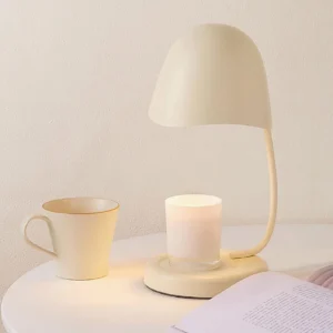 Sage green Breez table lamp on bedroom nightstand creating warm ambient candlelight with ceramic mug and scented candle