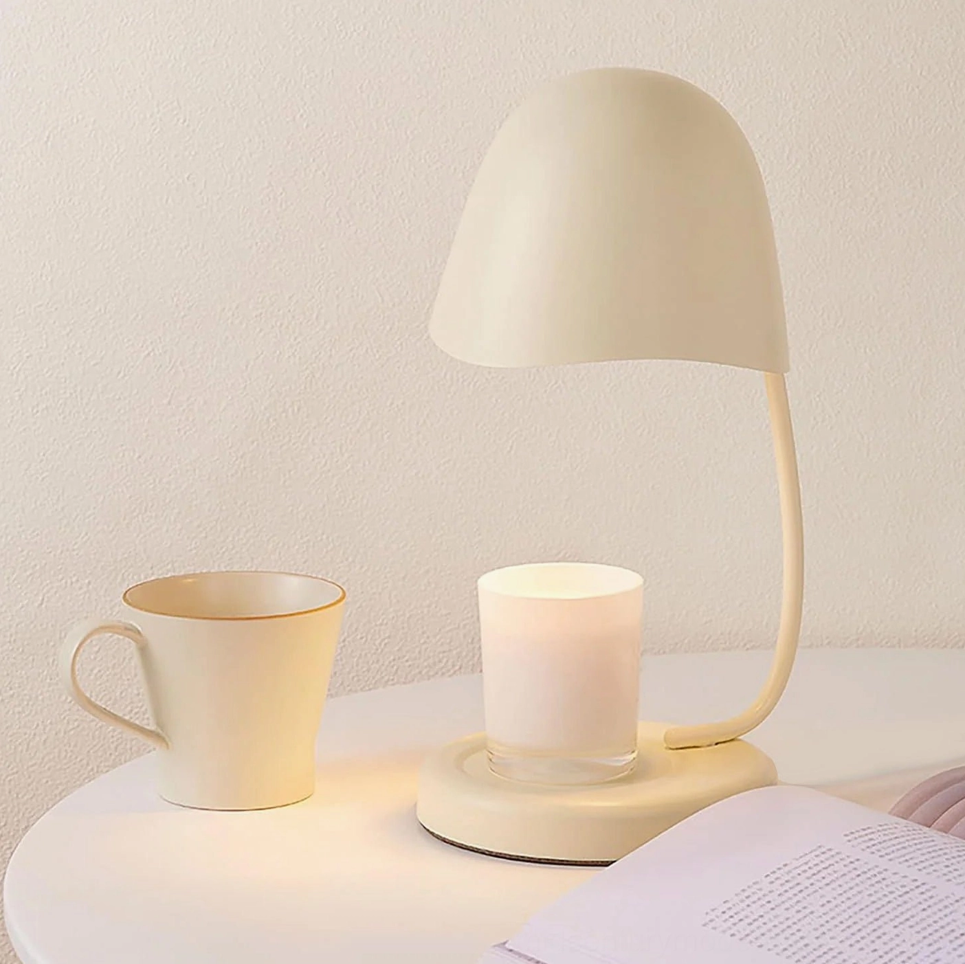 Sage green Breez table lamp on bedroom nightstand creating warm ambient candlelight with ceramic mug and scented candle