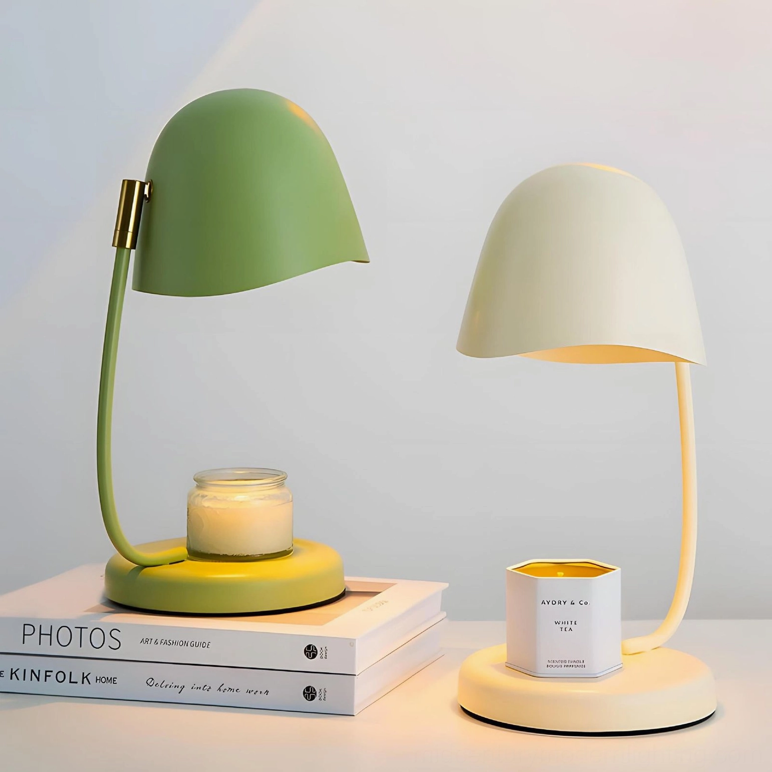 Dual Breez candle lamps in sage green and beige displayed together on stacked books tabletop arrangement