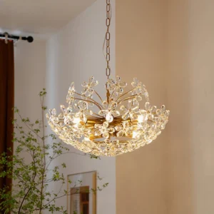 Gold floral crystal chandelier hanging in warm cozy living room with green plants and natural lighting