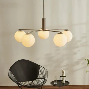 Brass sputnik chandelier Briette hanging in minimalist Nordic living room with warm opal glass shades and accent chair