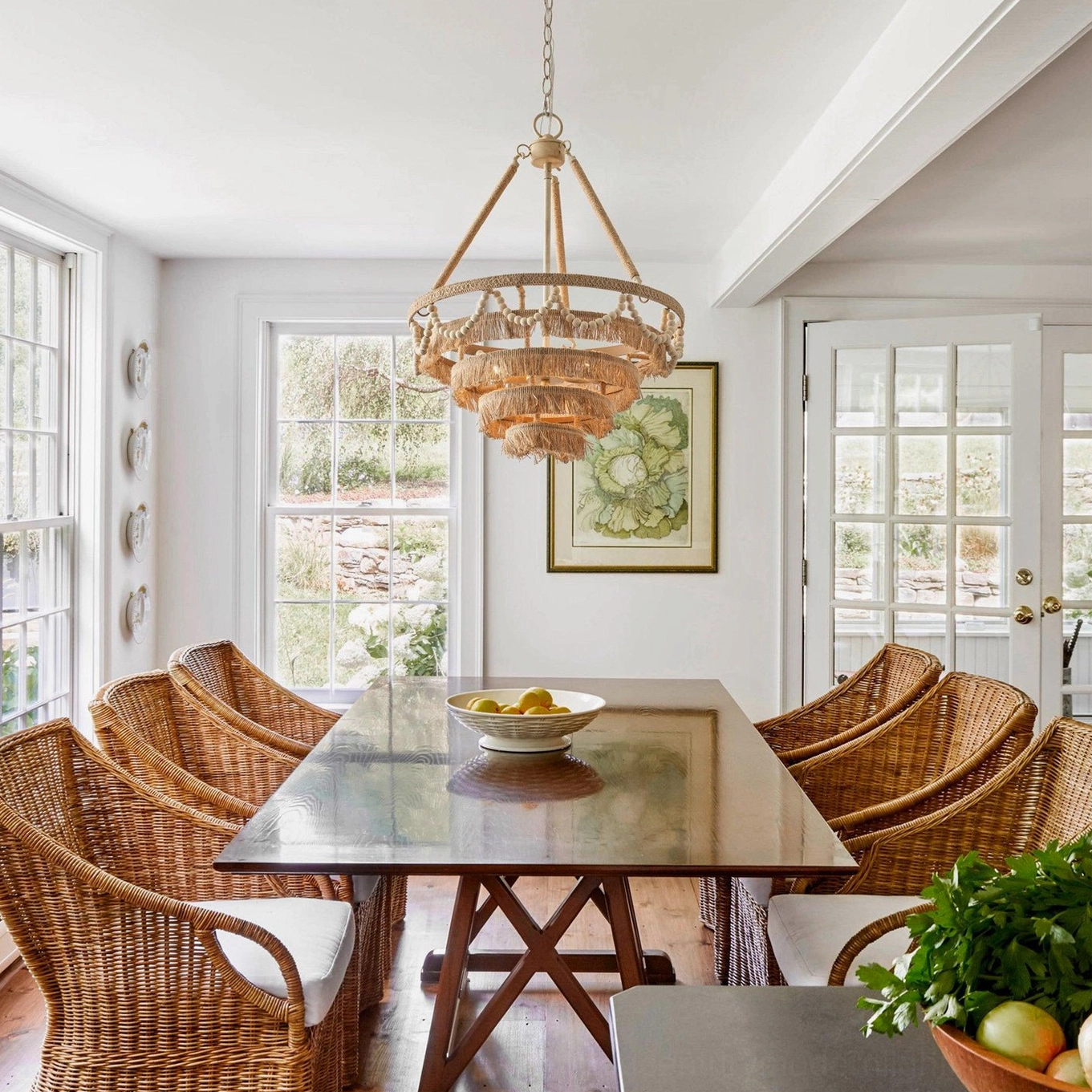 Bristol chandelier in farmhouse dining room above wicker chairs creating warm bohemian ambiance