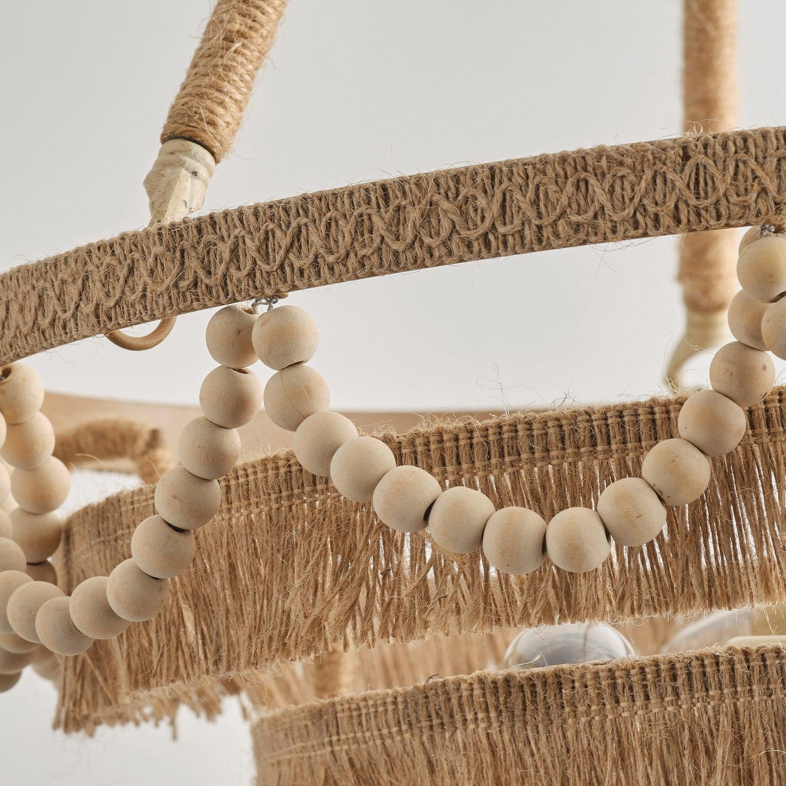 Close-up detail of Bristol chandelier jute trim, wooden bead accents, and tiered raffia fringe layers