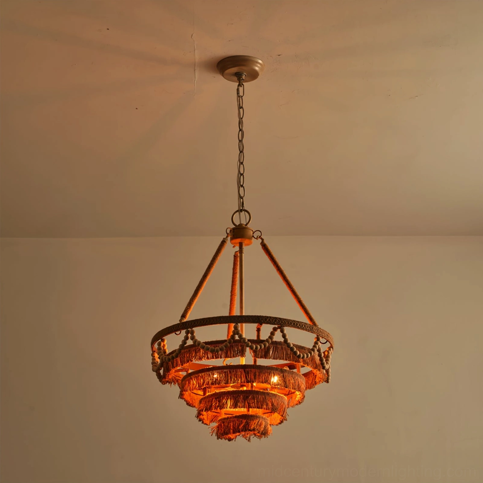 Illuminated Bristol chandelier with warm amber Edison bulbs highlighting natural jute and fringe details