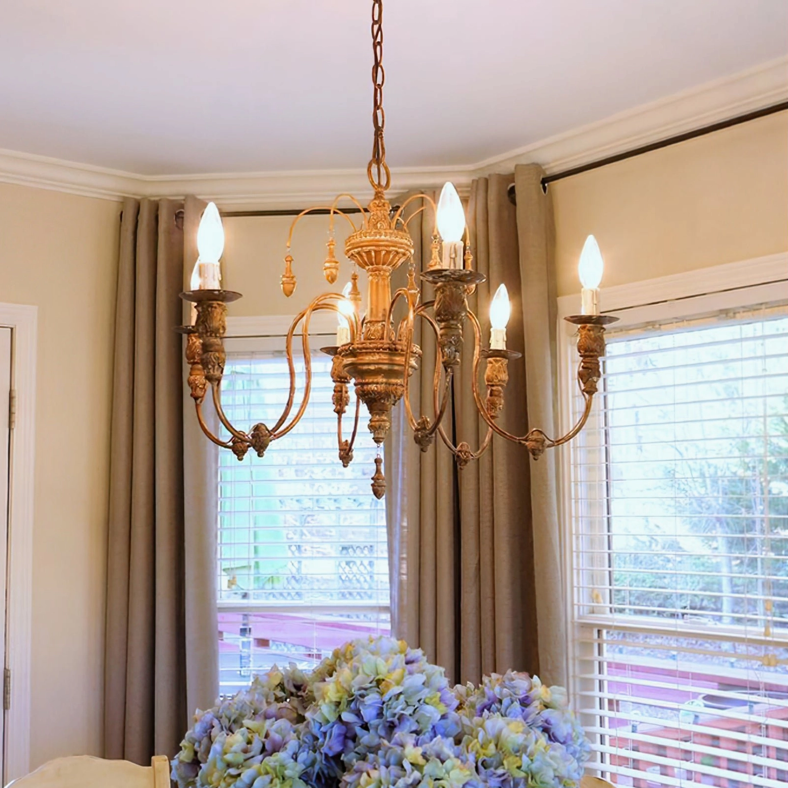 Vintage bronze candelabra chandelier in dining room with warm Edison bulbs and ornate metal carvings