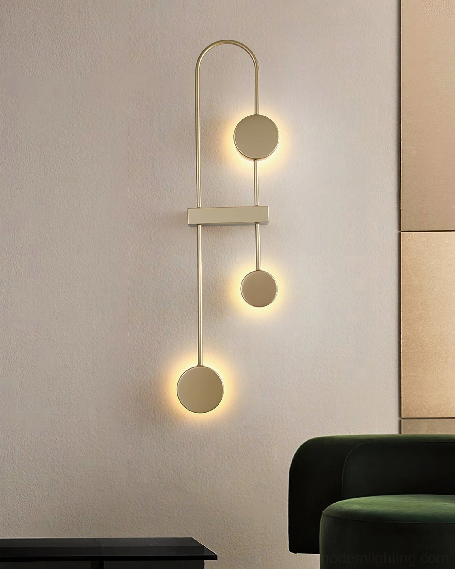Brushed gold geometric wall sconce with stacked spherical pendants in modern living room with green sofa