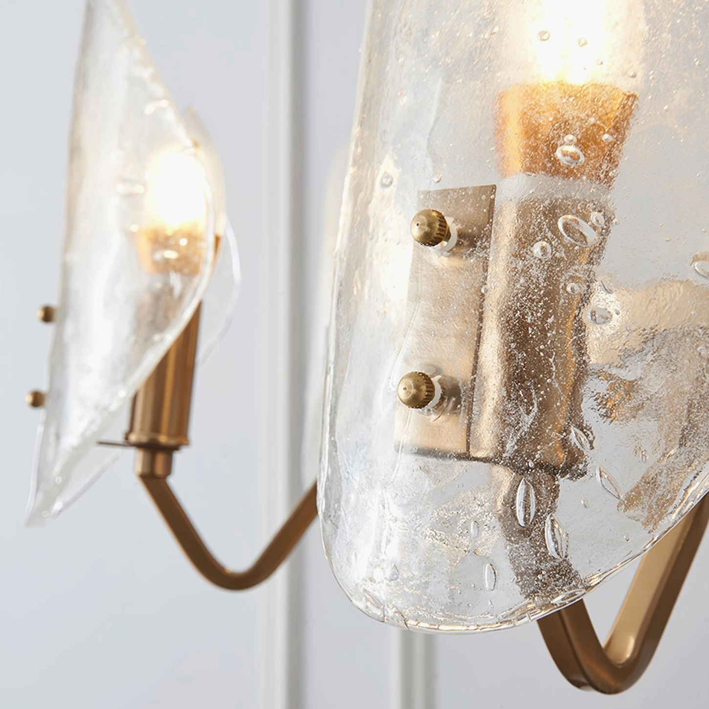 Extreme macro view of clear bubble textured glass and brass metal fixtures with lit candle bulbs