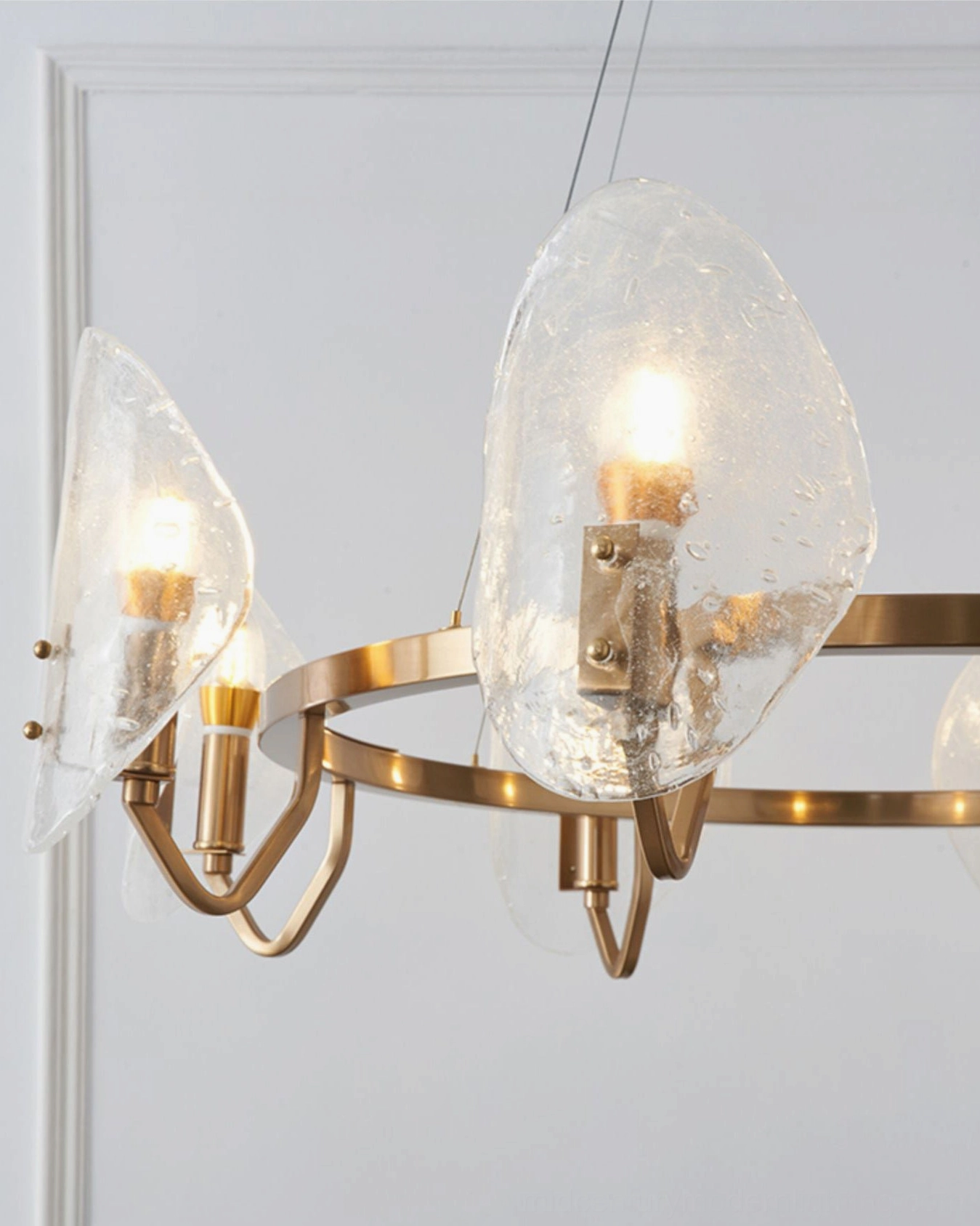 Side view of bubble glass chandelier showing curved gold metal arms and illuminated candle bulbs