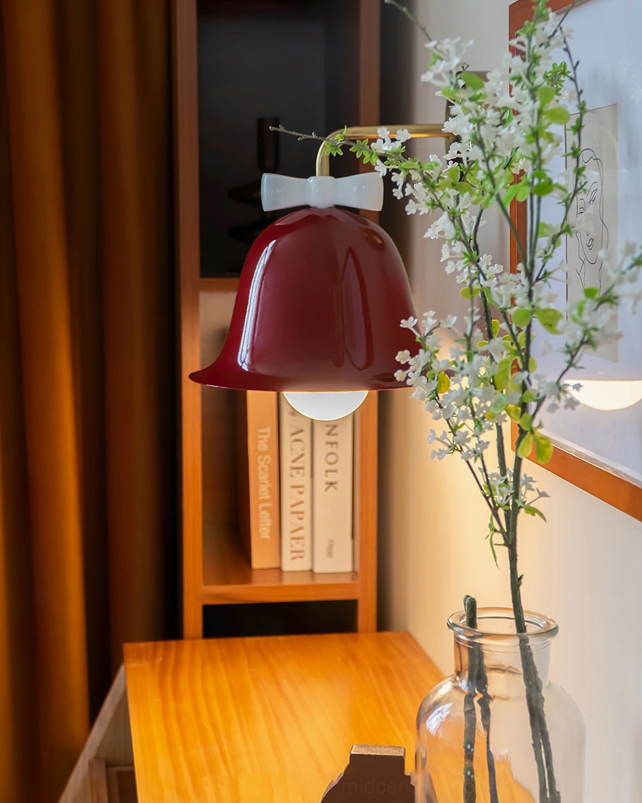 Low-angle close-up of burgundy Bow Bell Wall Lamp above home study desk with flowers and bookshelf
