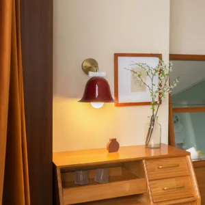 Burgundy red Bow Bell Wall Lamp installed above wooden vanity dresser in mid-century modern bedroom