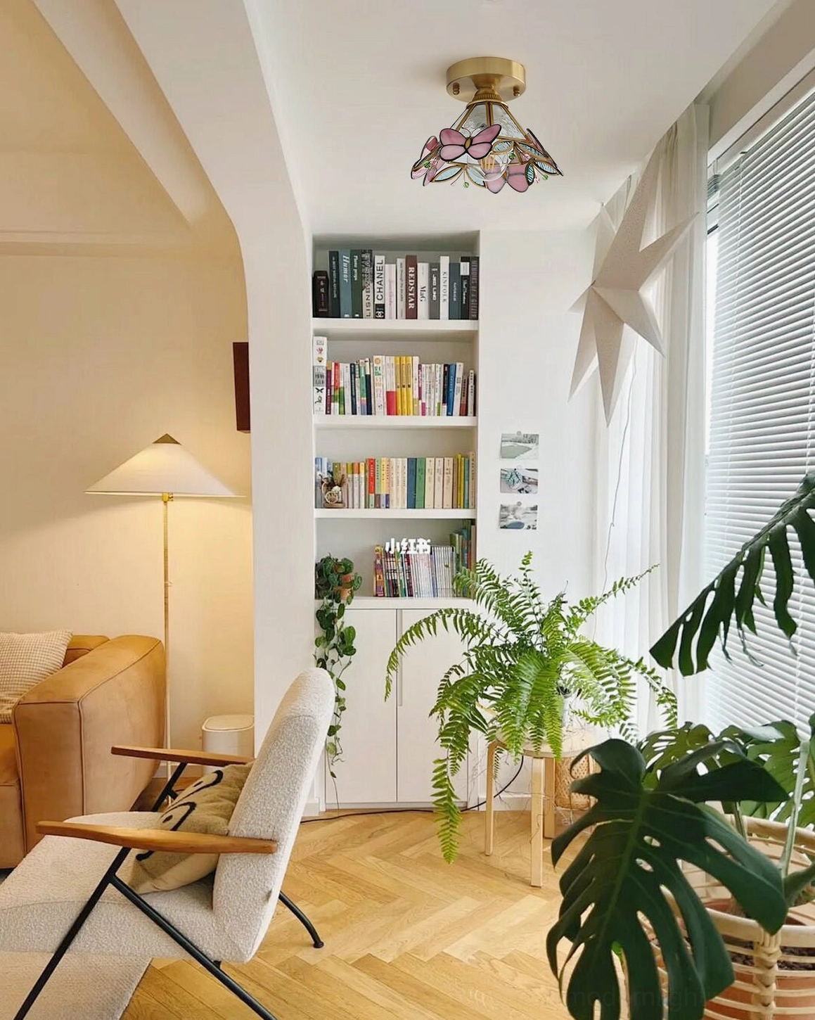 Butterfly stained glass ceiling fixture in cozy home study with bookshelf and plants, neutral modern style