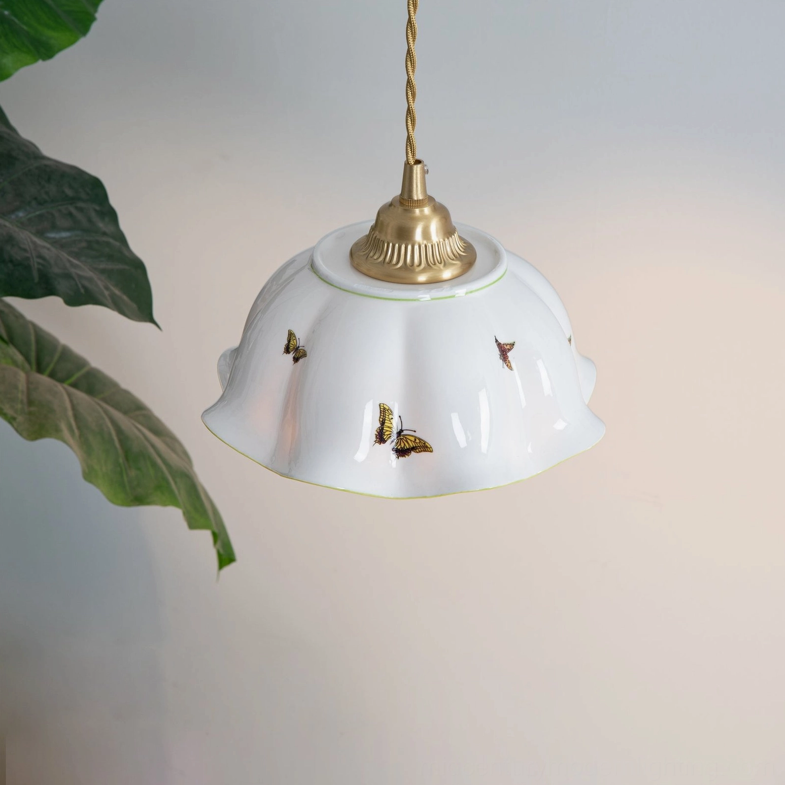 Underside view of ceramic butterfly pendant lamp showing brass fixtures and detailed butterfly pattern design