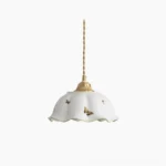 Butterfly ceramic pendant lamp with scalloped white shade and brass hardware on pure white background, front view