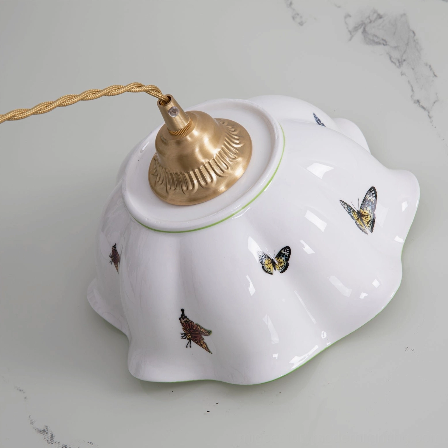 Top-down flat view of ceramic butterfly pendant shade upside down on marble surface showing full butterfly print pattern