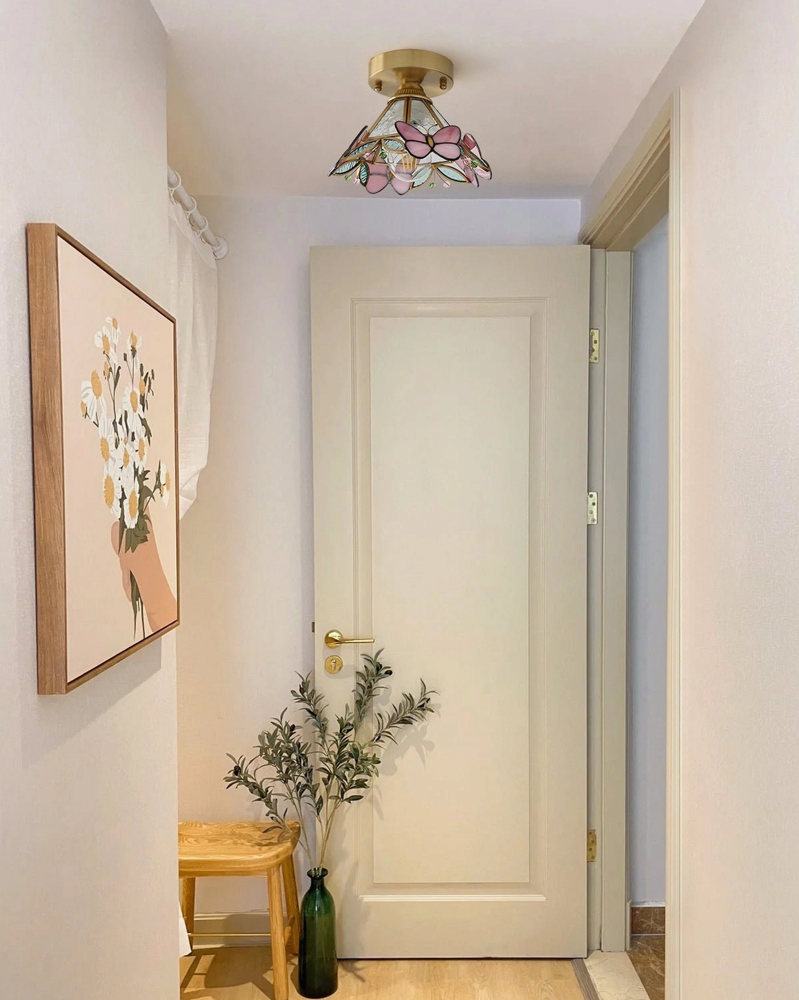 Stained glass butterfly ceiling lamp illuminating contemporary home entryway with wall art and minimal furnishings