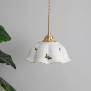 White ceramic pendant light with green trim and butterfly prints displayed in modern interior with tropical plants
