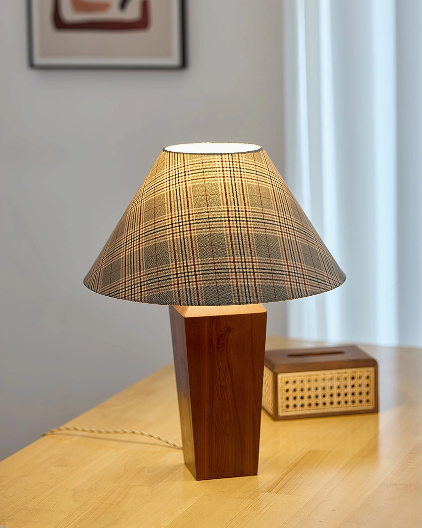 Lit cabin table lamp emitting warm glow on home desk with wall art and woven storage boxes, cozy ambiance