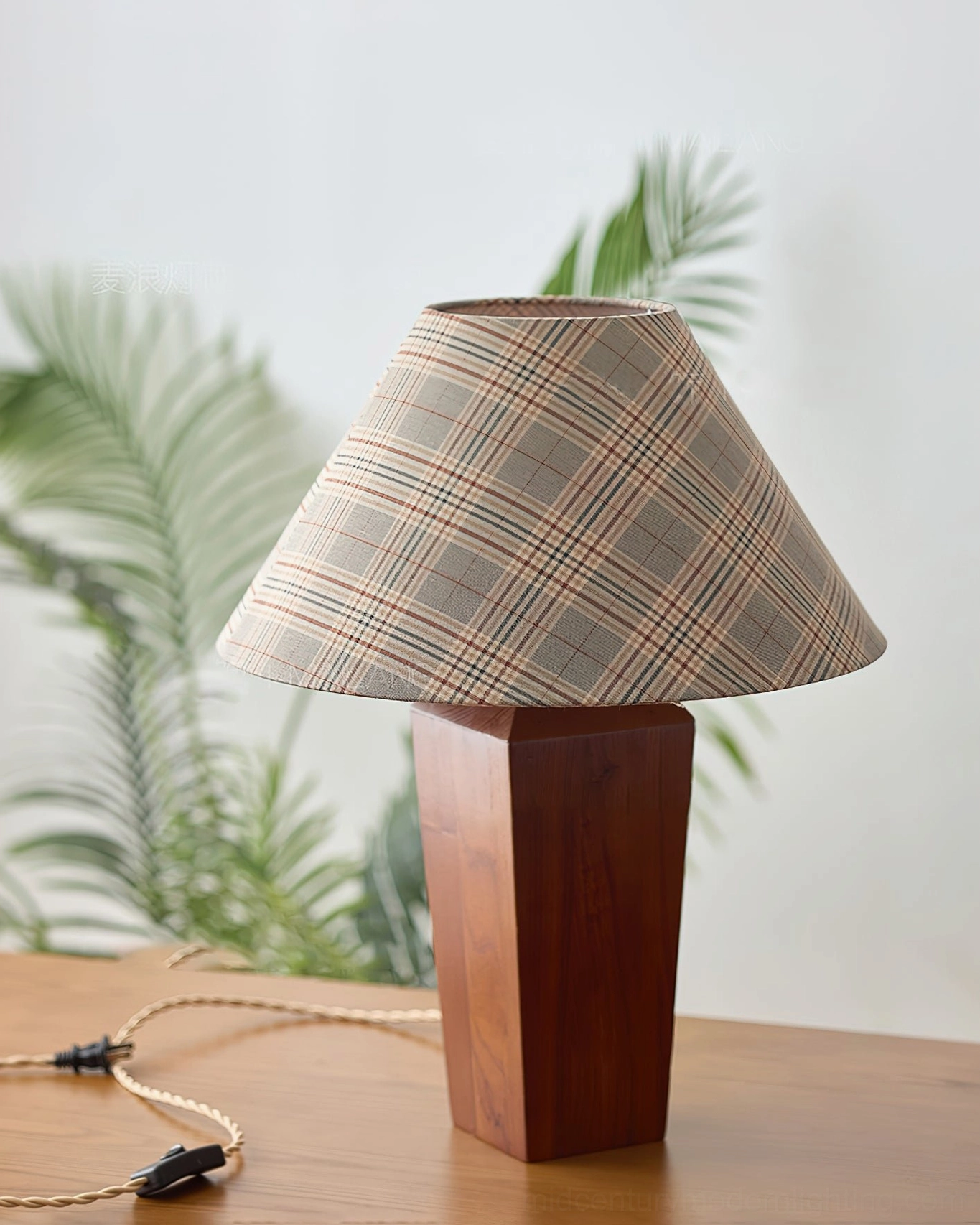 Cabin table lamp with neutral red plaid shade on desk near green plants, three-quarter view
