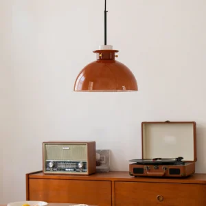 Cabras pendant light installed in vintage home dining corner, side high angle view showing black suspension rod and warm amber glow